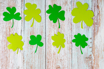 Green clover leaves cut from paper on a wooden background. Greeting topview pattern with copyspace for St. Patrick's Day. Topview