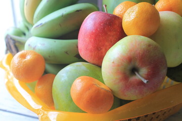 Bananas, oranges, mangoes and apples in plastic containers on the table