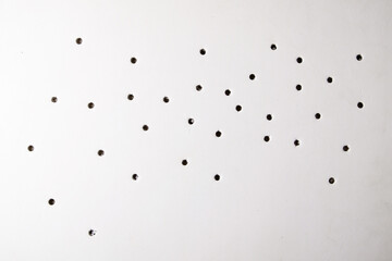 Bullet damage on white foam board, background with through holes.
