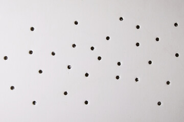 Bullet damage on white foam board, background with through holes.