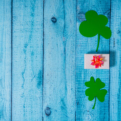 Green clover leaves and giftboxes on a wooden backgaund. St. Patricks postcard with copyspace. Topview