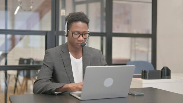 African American Man with Headset Working on Laptop