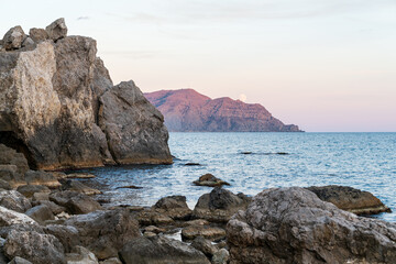 Fototapeta na wymiar Sudak, Crimea. Moon rise. Cape Rybachy. Mount Meganom in the light of the setting sun