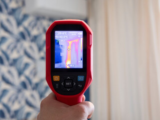 A specialist conducts a thermal imaging examination inside the building. Search for heat losses. Inspection of the walls of the room to eliminate deficiencies and insulate problem areas