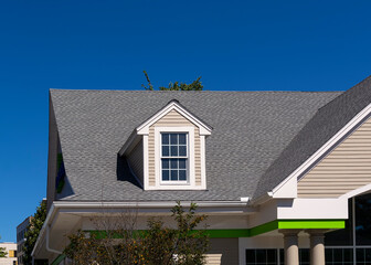 Gabled dormer window on the sloped shingle roof of a newly built family house in Boston, MA, USA © Baharlou