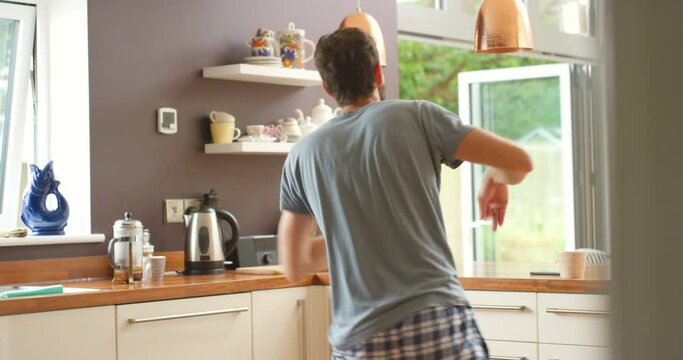 Happy, dance and man in a kitchen with music, fun and freedom, streaming or entertainment at home. Morning, energy or excited male person moving to groovy track, audio or radio celebration in a house