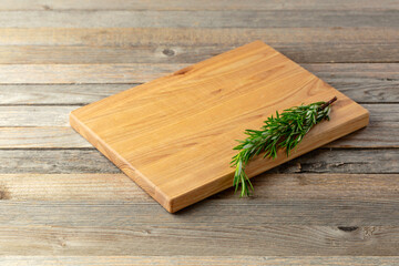 Cutting board and rosemary on an old wooden table.