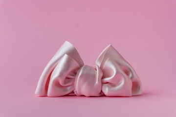 Close up shot of pink bow made of mastic sugar paste on a pink background. Homemade cake decoration for a little girl