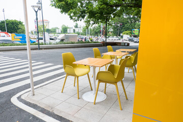 Yellow steel chairs and tables near street in city.