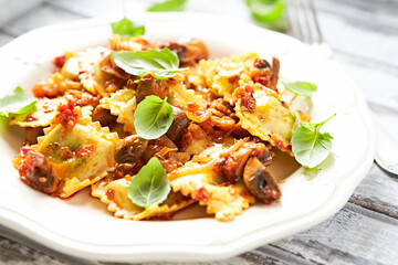 Ravioli with mushrooms and fresh basil. Bright wooden background. Close up.	