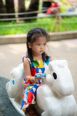 Adorable beautiful asian little girl playing outdoor playground Active kid on colorful slide and swing.