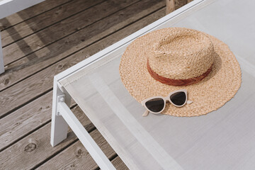 Relaxing and sunbathing concept. Straw hat, sunglasses on sun lounger. Summer vacation holidays at...
