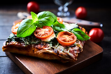 Open-faced toasted cheese sandwich with cherry tomatoes, spinach and fresh basil. Brown wooden background.	