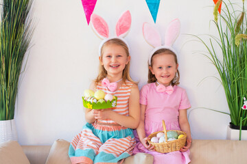 children in bunny clothes sitting on the sofa at home and watching Easter eggs
