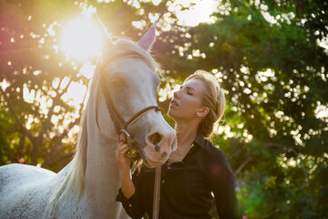 beautiful young female jockey with blond hair with a white Arabian horse.	