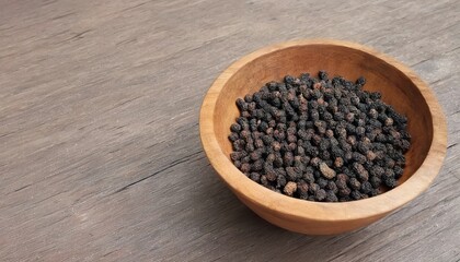 organic kampot dried black pepper corns in traditional wood bowl in cambodia