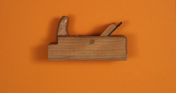 Vintage wood plane making a shaving on color background. Loopable stop motion animation. 4K top view. DIY video concept.