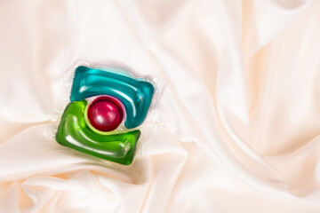 Liquid detergent gel in capsule on fabric close-up, space for text