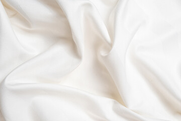 Fototapeta premium Waves and patterns of crumpled natural satin white milk color fabric.