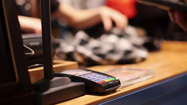 Contactless Payment in Retail. A customer uses his smartphone to make a contactless payment at a store terminal, showcasing modern convenience and technology in retail transactions