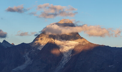 Mountain peak with glacier at sunset and a few clouds