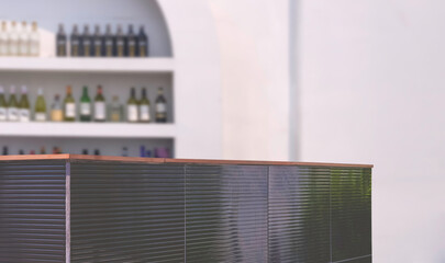 Focus at bar counter with blurred background of liquor shelf on white wall of outdoor pub