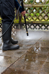 person is using a pressure washer to clean a brick patio