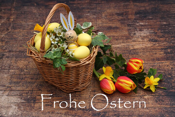 Grußkarte Frohe Ostern: Ostereier und Blumen in einem Korb mit der Aufschrift Frohe Ostern.