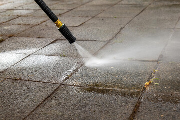 pressure washer is spraying water on a dirty sidewalk