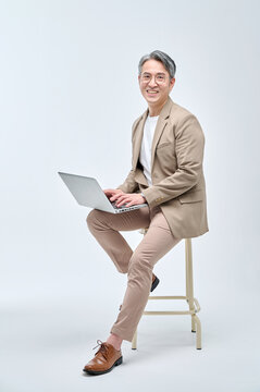 A middle-aged male teacher in a suit and glasses is sitting in a chair, holding a laptop, working with various expressions and poses.
