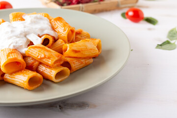 Macaroni with tomato sauce and stracciatella. Good and balanced Italian cuisine dish