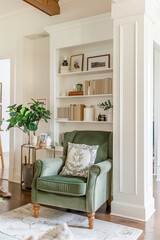 A green velvet chair in the corner of an open concept living room with built-in shelves, white walls, and light wood floors, farmhouse style home decor photography in the style of farmhouse style.