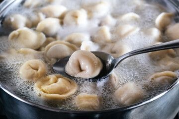 Dumplings are boiled in a pot of boiling water. Close-up.