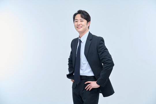A young office worker man in a navy suit is posing with various facial expressions.