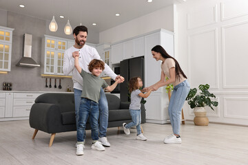 Happy family dancing and having fun at home, low angle view