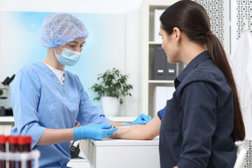 Laboratory testing. Doctor taking blood sample from patient at white table in hospital