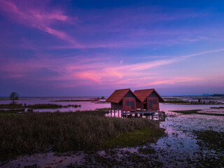 Landscape image of Abandoned twin house near Chalerm Phra Kiat road at sunset in Thale Noi, Phatthalung, Thailand