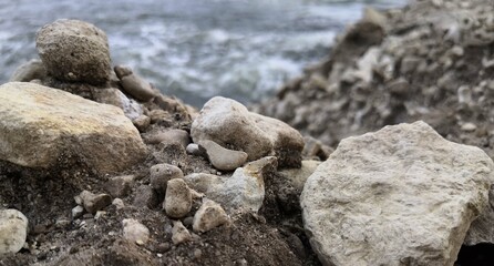 Rock Formation by Beach With Water in Background
