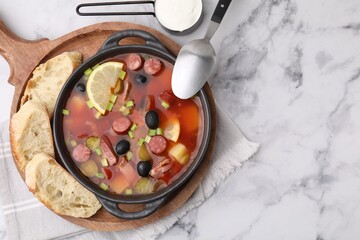 Meat solyanka soup with thin dry smoked sausages served on white marble table, flat lay. Space for text