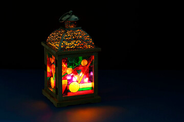 Decorative Arabic lantern on table against dark background. Space for text