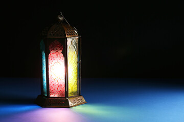 Decorative Arabic lantern on table against dark background. Space for text