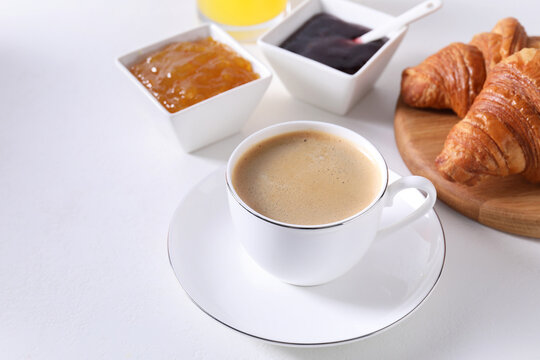 Breakfast time. Fresh croissants, jams and coffee on white table. Space for text