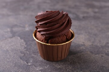 Delicious chocolate cupcake on grey textured table, closeup