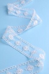 White lace on light blue background, closeup view
