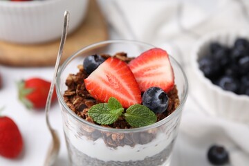 Tasty granola with berries and yogurt in glass on table, closeup