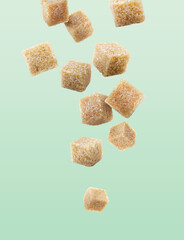Brown cane sugar cubes falling on turquoise gradient background