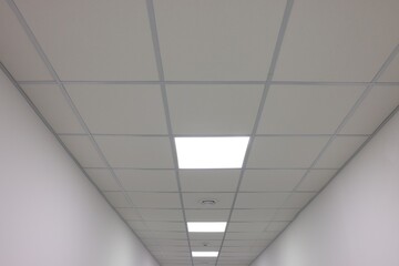 White ceiling with PVC tiles and lighting indoors, low angle view