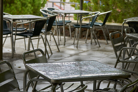 Detail of the metal table of a restaurant on a terrace raining with the surface of the table wet and in the background more wet tables out of focus