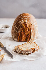 Gebackener Brotlaib und Scheiben auf einem weißen Backpapaier. Österreich, hausgemacht.