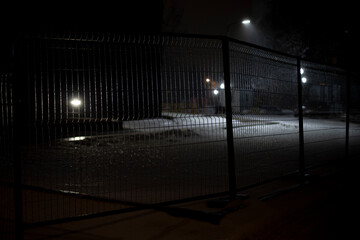 Fence around the parking lot at night. Territory at night. Mesh fence.
